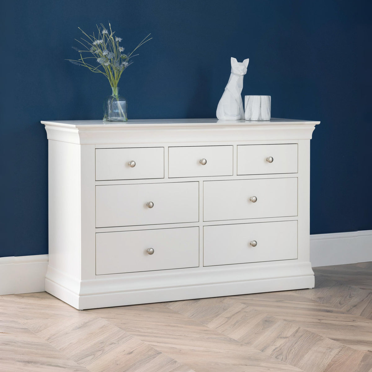White dresser with decorative items against a blue wall