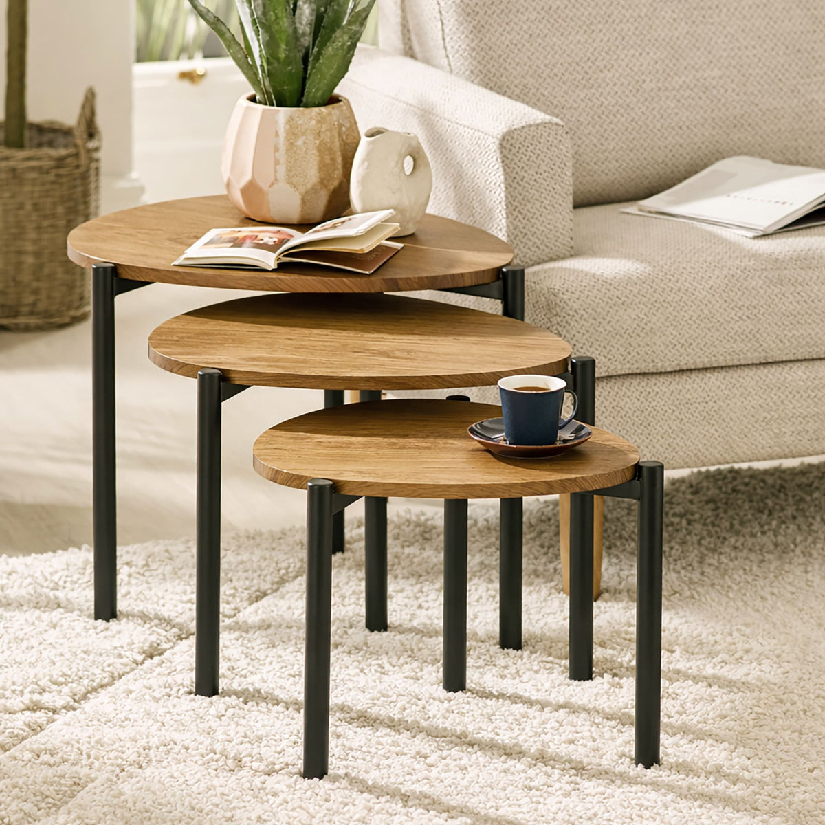 Set of three wooden nesting tables with black legs in a living room setting.