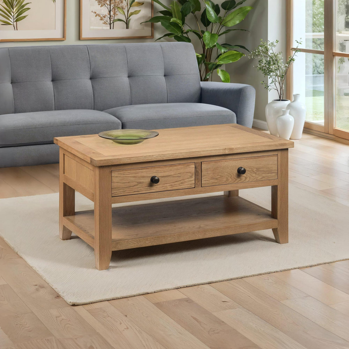 Wooden coffee table with two drawers in a living room setting with a gray sofa and plants.