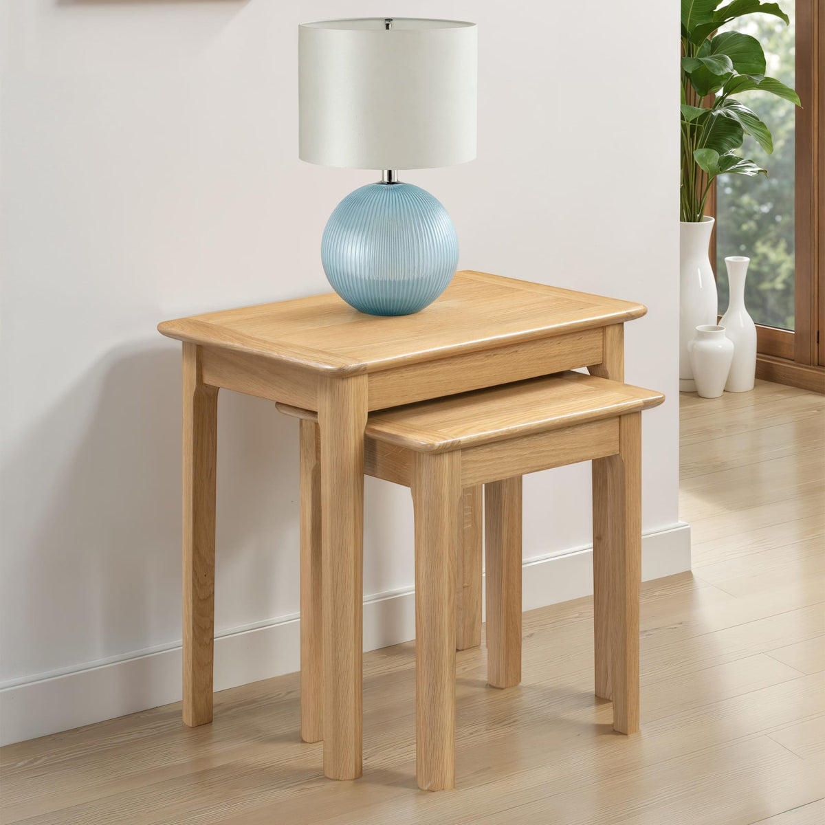 Two wooden side tables with a lamp on a light wood floor.
