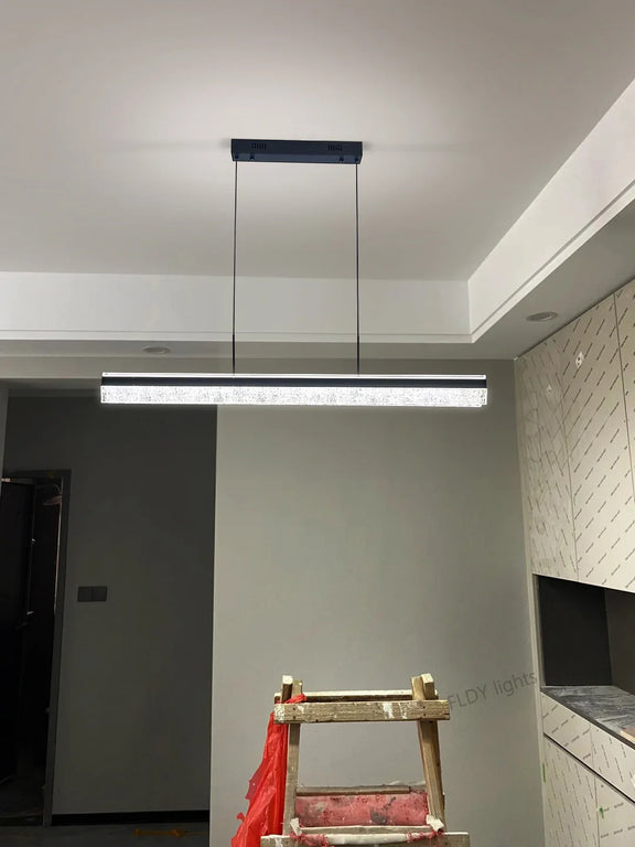 Crystal linear LED pendant light in black finish hanging over dining table