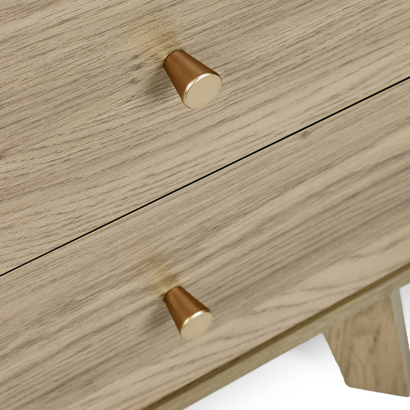 Wooden drawer with gold knobs on a light wood background