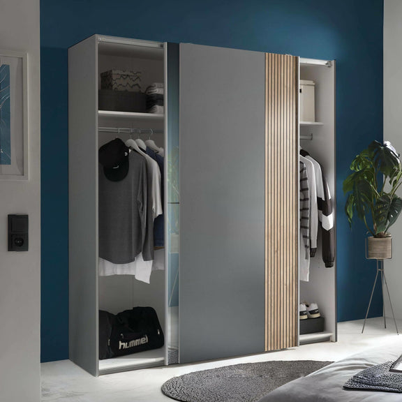 Gray wardrobe with wooden accents in a room with blue walls and a plant.