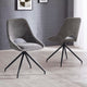 Two gray upholstered chairs with black metal legs on a light wooden floor against a gray brick wall.