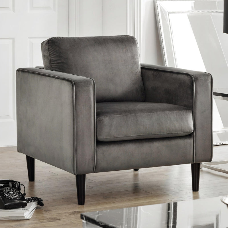 Gray armchair in a room with a white wall and wooden floor.