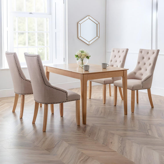 Dining room with wooden table and four beige chairs in a bright room.
