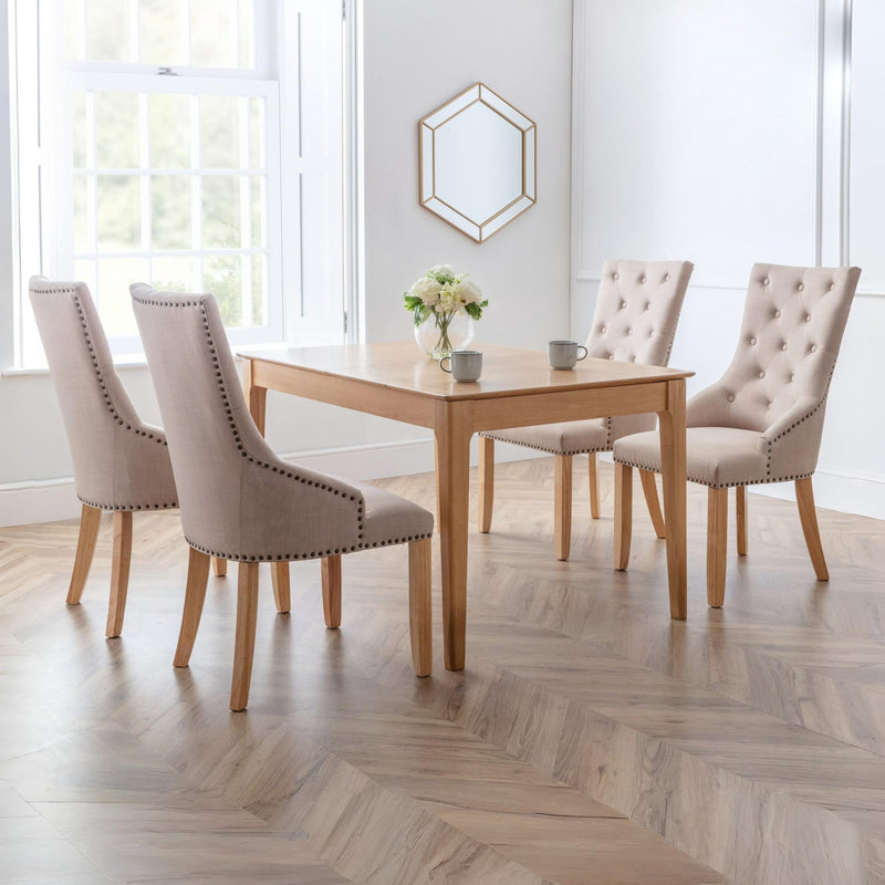 Dining room with wooden table and four beige chairs in a bright room.
