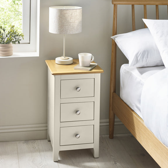 White wooden 3 drawer bedside table with oak top beside bed