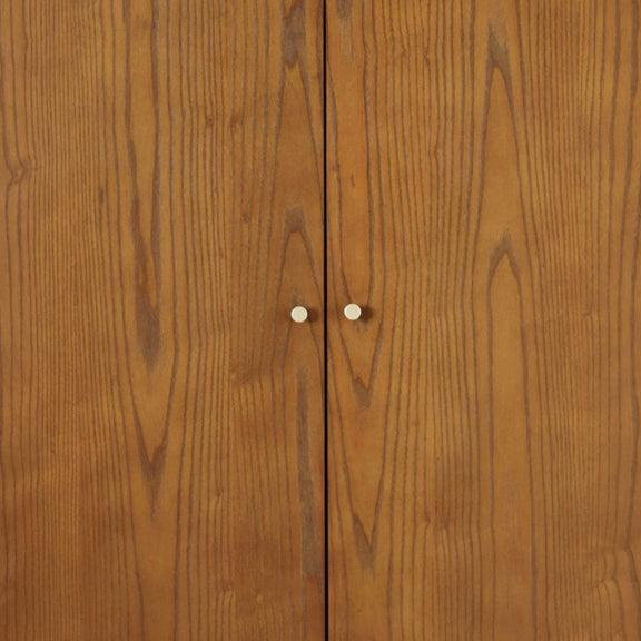 Close-up of a wooden cabinet with a visible joint and two small white knobs.