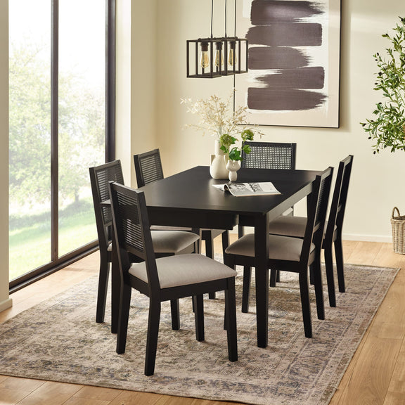 Dining room with a black table and chairs on a patterned rug.