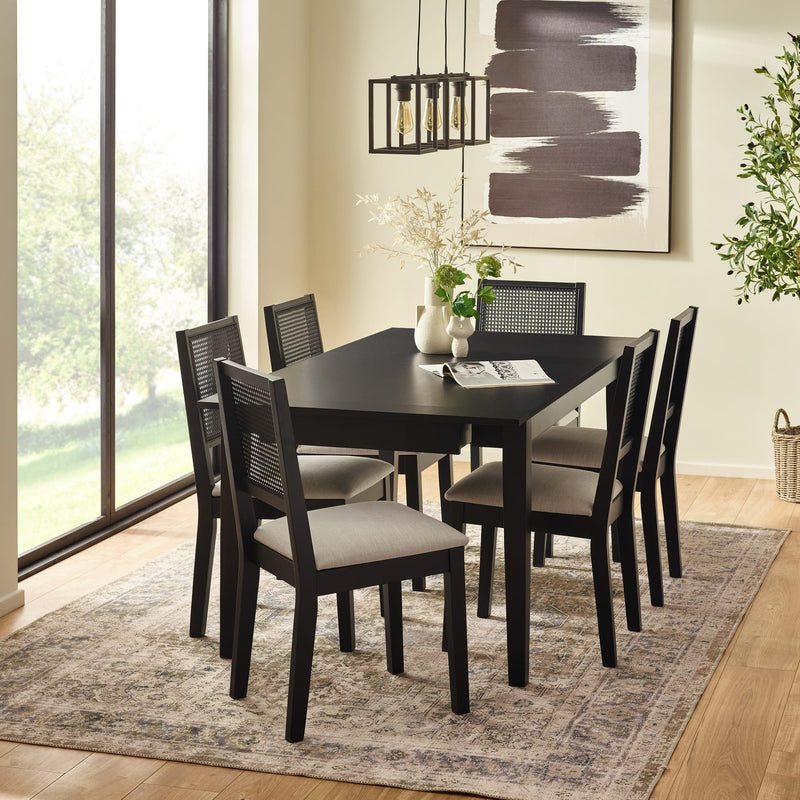 Dining room with a black table and chairs on a patterned rug.