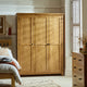 Wooden wardrobe in a bedroom setting with a bed and dresser.