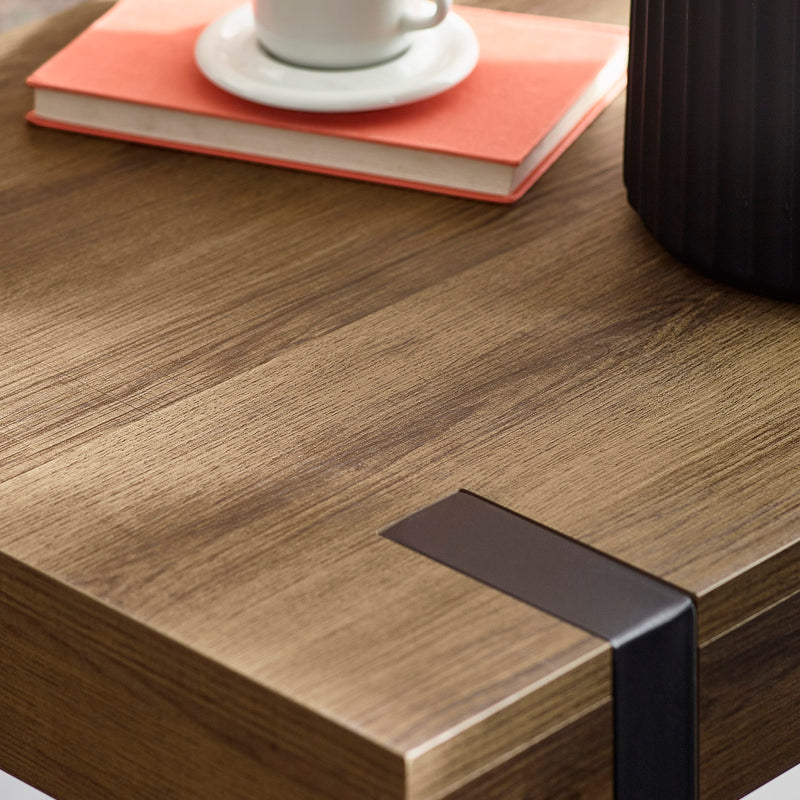 Wooden desk surface with a black metal leg and a book and cup on top.