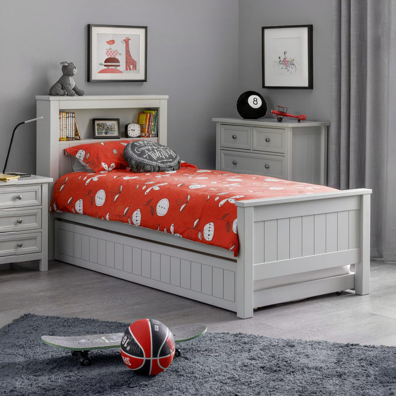 Children's bedroom with a white bed, red bedding, and various toys.