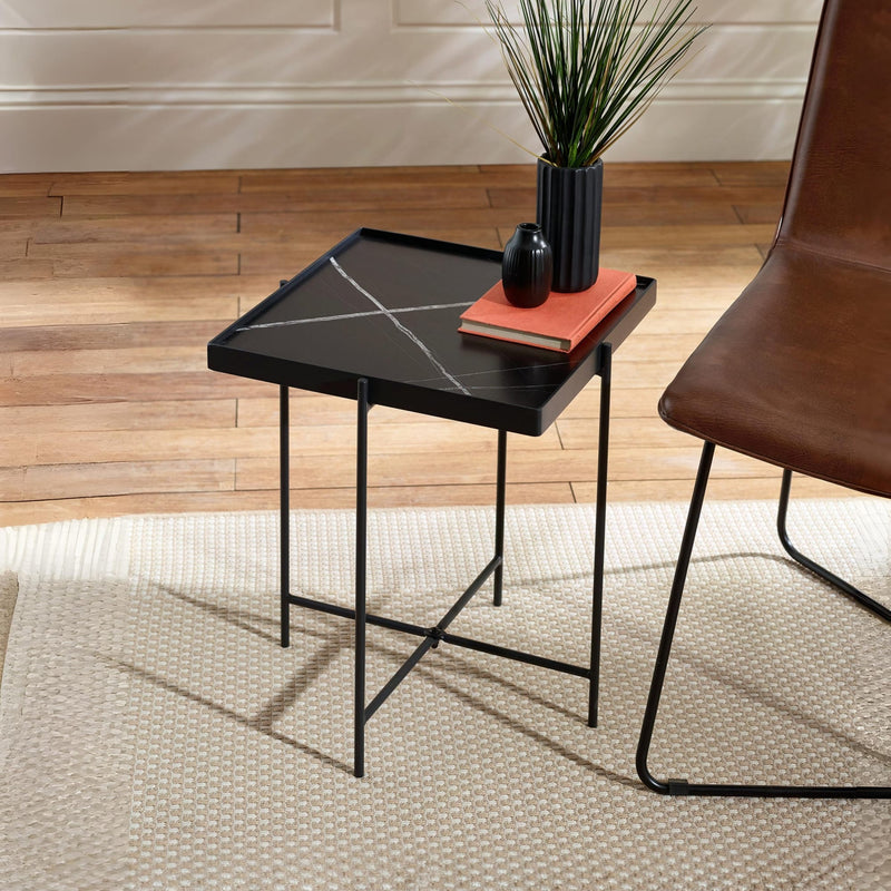 Black marble-patterned side table with a brown chair and decorative items on a wooden floor.