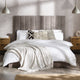 Neatly made bed with white bedding and decorative pillows in a bedroom setting.