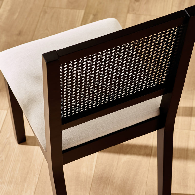 Chair with woven backrest and white cushion on a wooden floor