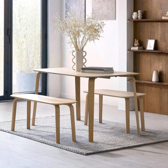 Dining table with two benches and a vase of flowers in a modern room.