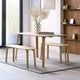 Dining table with two benches and a vase of flowers in a modern room.