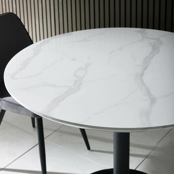 Round marble table with a black chair on a tiled floor