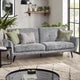 Gray sofa with decorative pillows in a living room setting with plants and a coffee table.