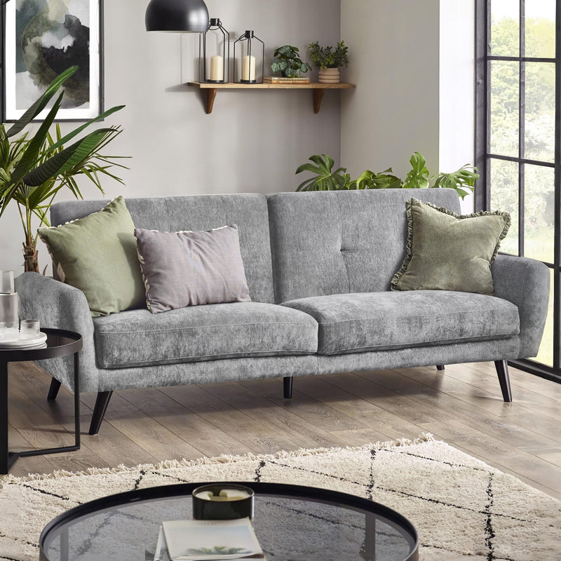 Gray sofa with decorative pillows in a living room setting with plants and a coffee table.