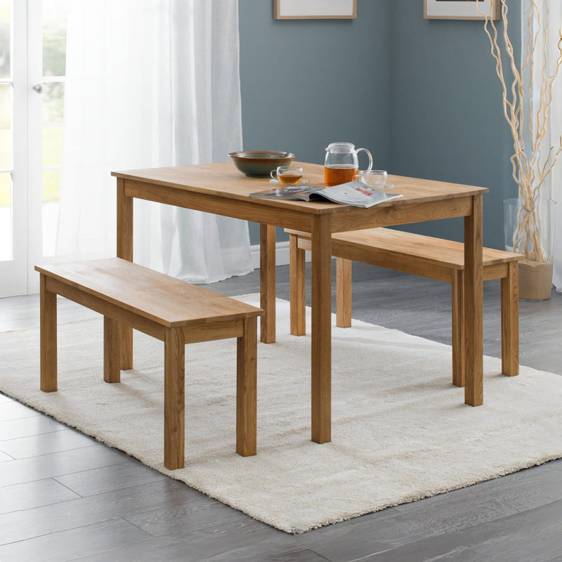 Wooden dining table with two benches in a room with a gray wall and white curtains.