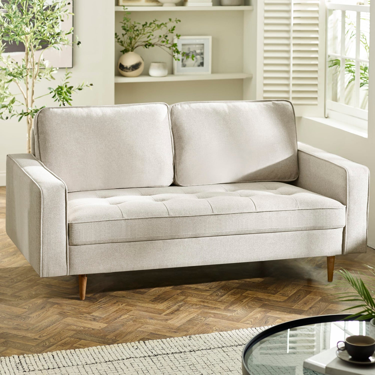 Gray sofa in a living room setting with a wooden floor and decorative elements.