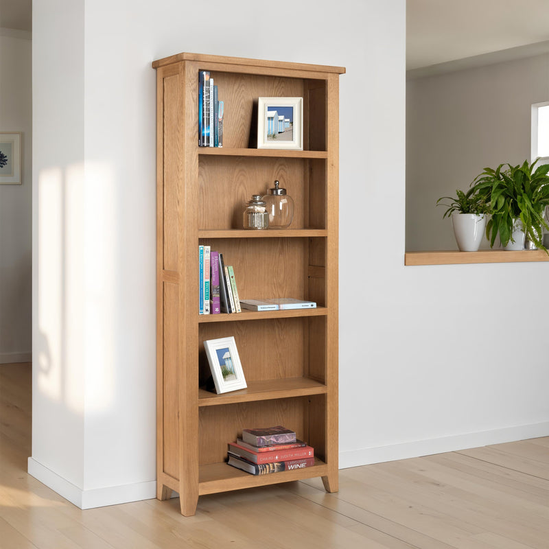 Wooden bookshelf with books and decor items against a white wall.