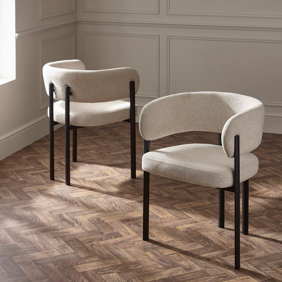 Two modern chairs with beige cushions and black frames on a wooden floor.