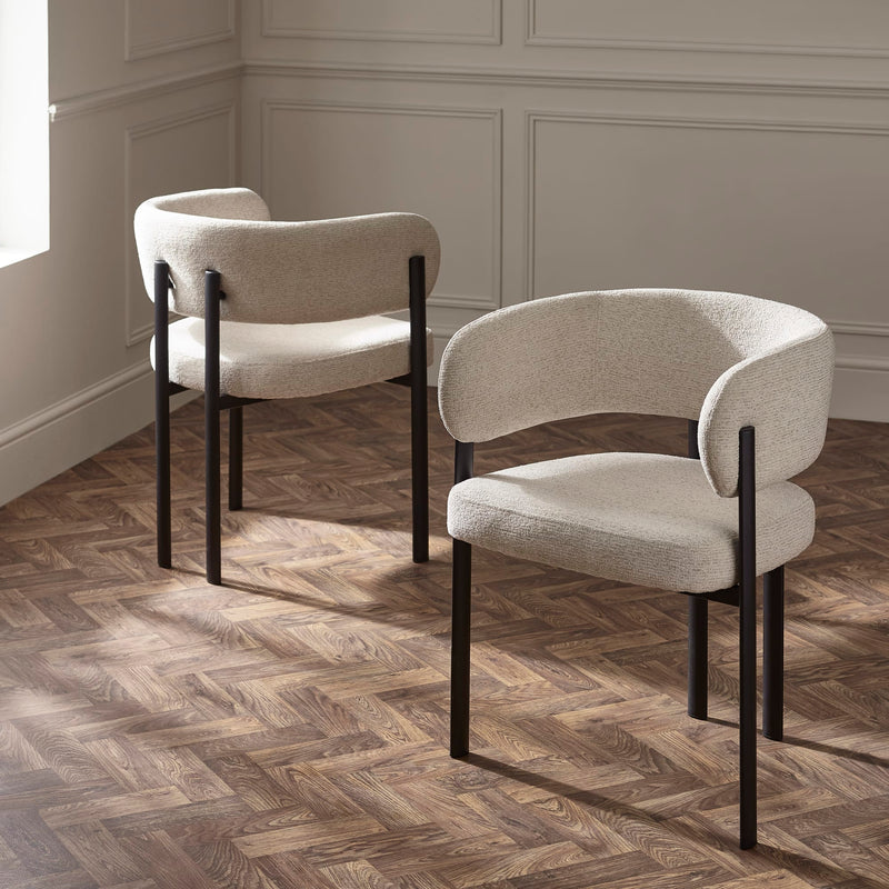 Two modern chairs with beige cushions and black frames on a wooden floor.