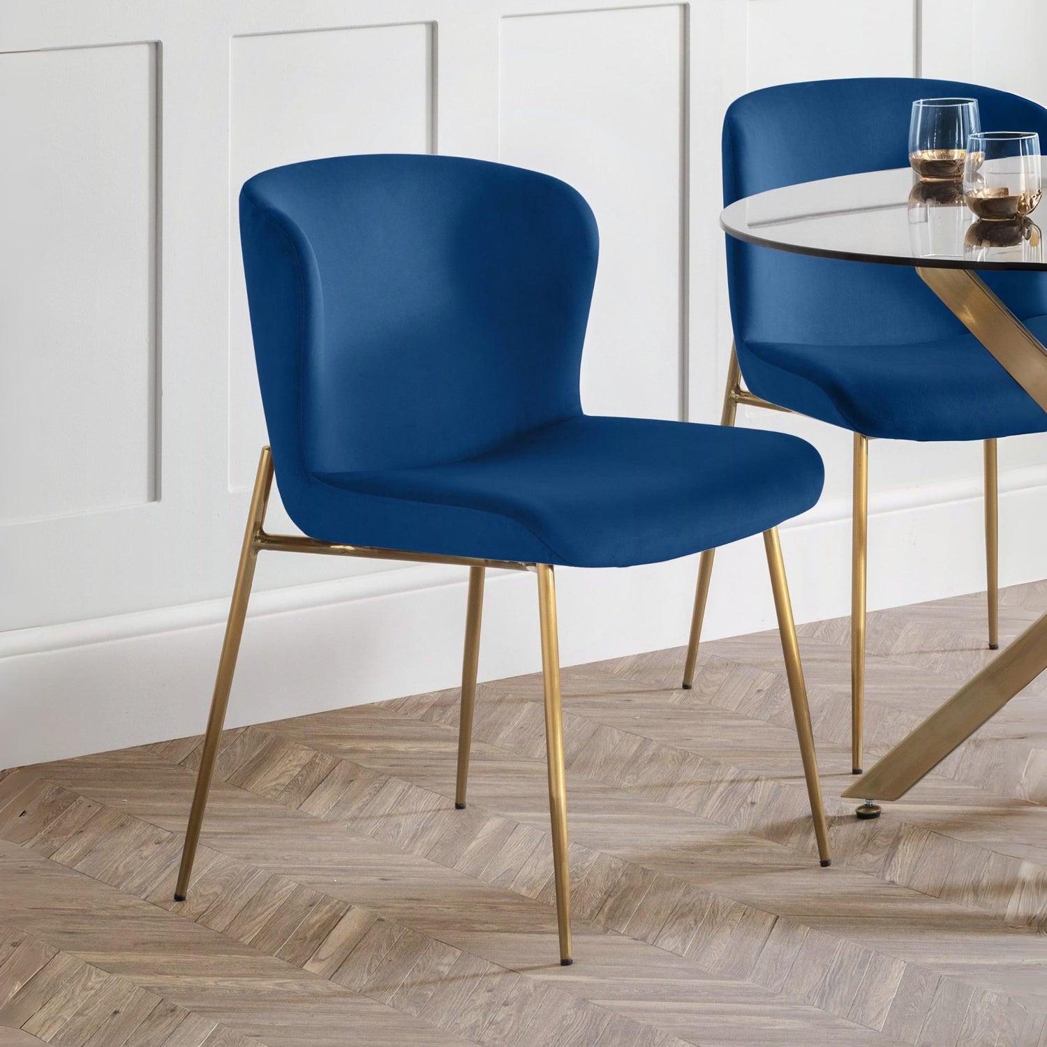 Blue chairs with gold legs in a room with a white paneled wall and wooden floor.