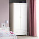 White wardrobe in a bedroom with pink curtains and a bed.