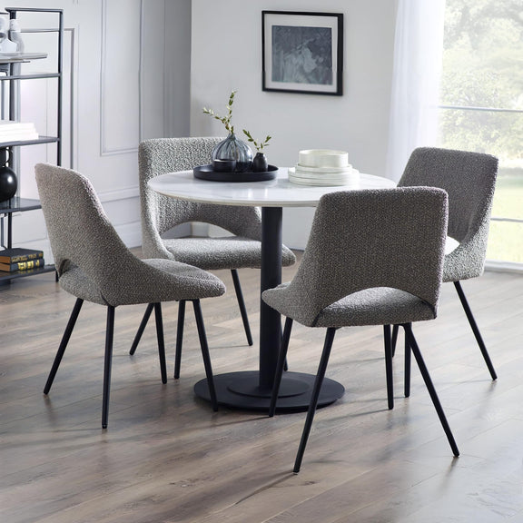 Dining room with a round table and four gray chairs on a wooden floor.