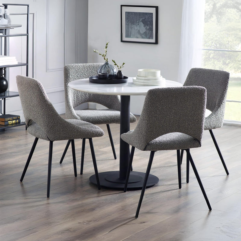 Dining room with a round table and four gray chairs on a wooden floor.