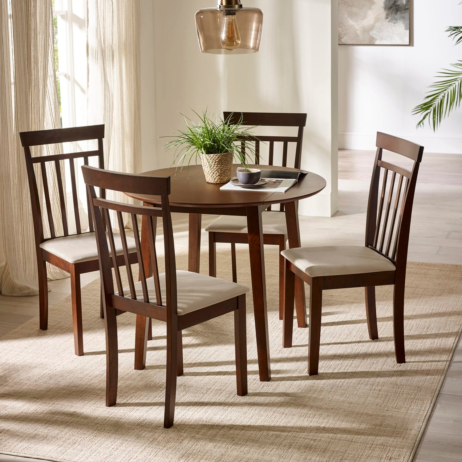 Dining room with a round wooden table and four matching chairs with white cushions.