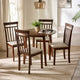 Dining room with a round wooden table and four matching chairs with white cushions.