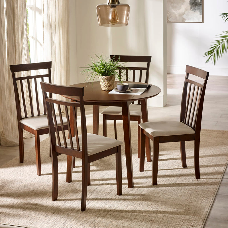 Dining room with a round wooden table and four matching chairs with white cushions.