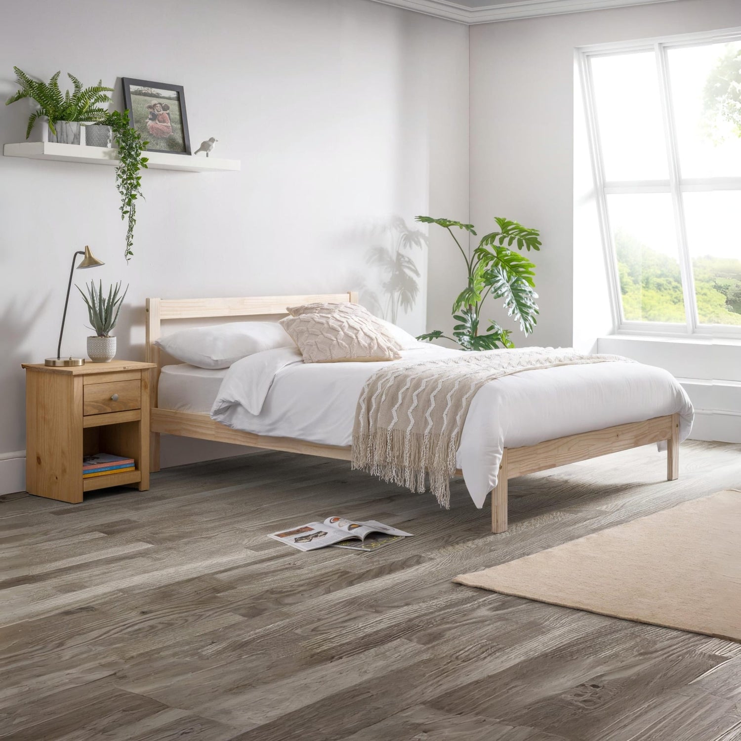 Bedroom with wooden bed and nightstand, white bedding, and plants.