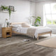 Bedroom with wooden bed and nightstand, white bedding, and plants.