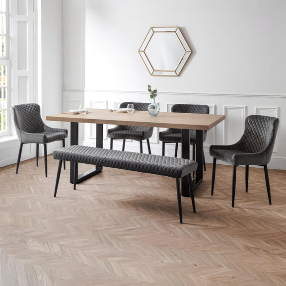 Dining room with wooden table, gray chairs, and bench on a wooden floor.