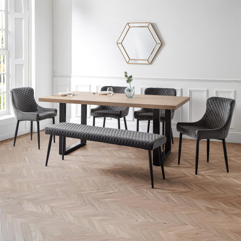 Dining room with wooden table, gray chairs, and bench on a wooden floor.