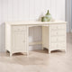 White wooden desk with drawers and a cabinet against a white paneled wall.