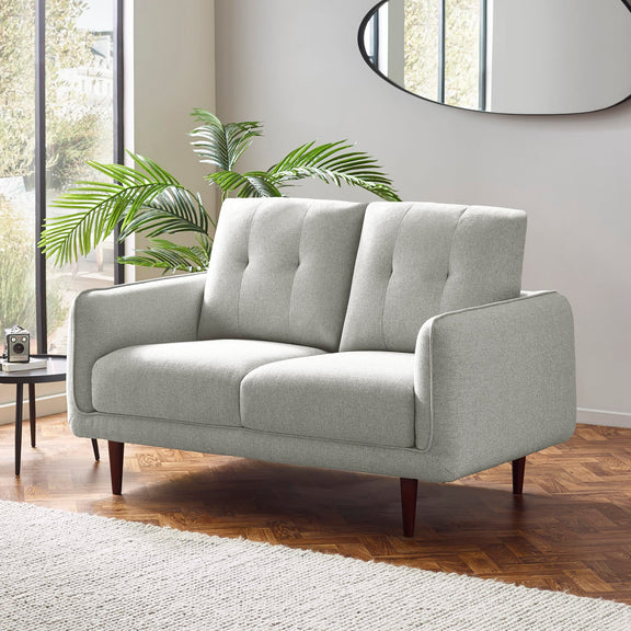 Gray sofa in a modern living room with plants and a mirror.