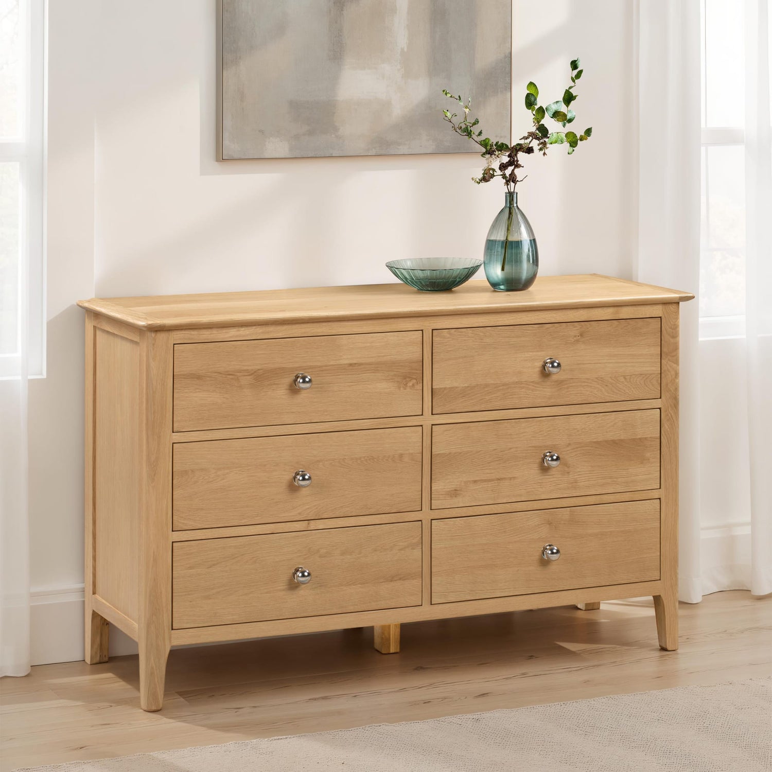 Wooden dresser with six drawers in a room setting.