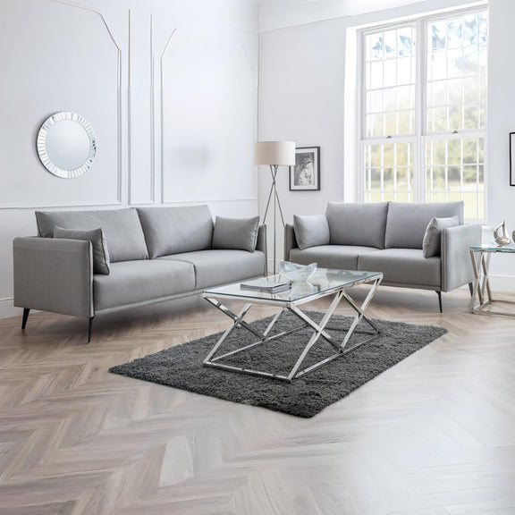 Modern living room with gray sofas, a glass coffee table, and decorative elements.