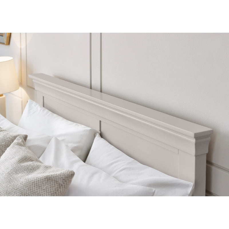 Wooden headboard against a white wall with pillows on a bed.