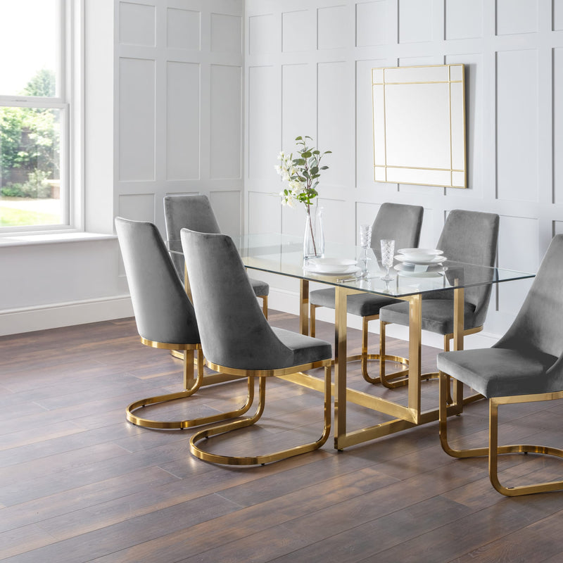 Dining room with a glass table and gray chairs on a wooden floor.