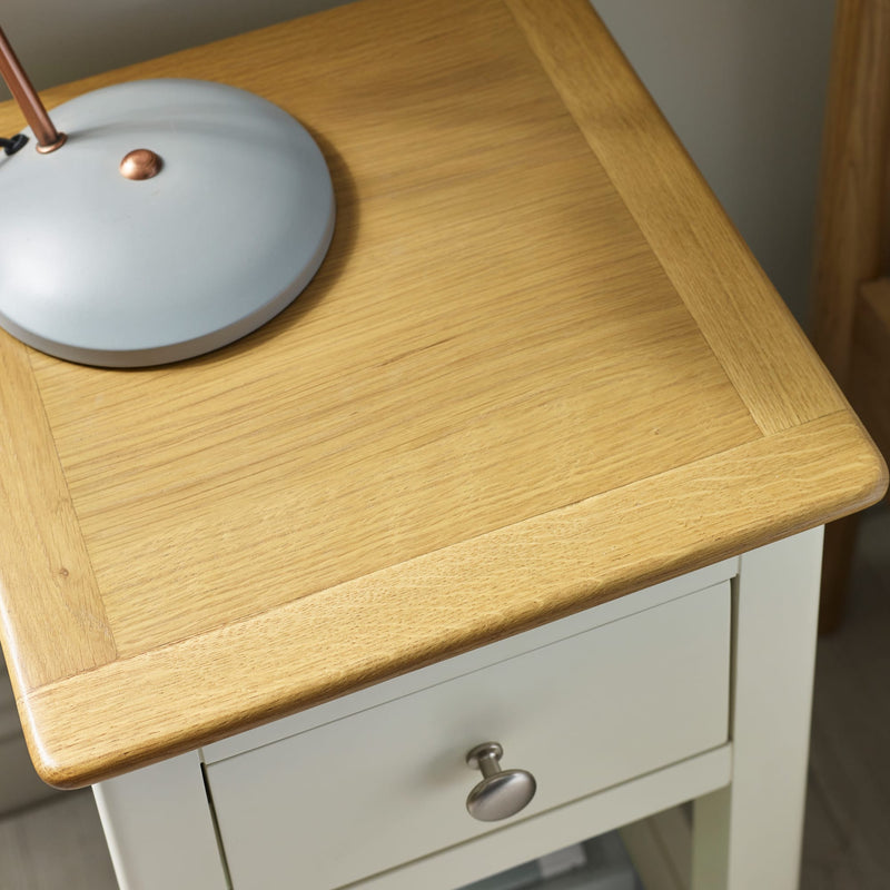 Wooden table with a lamp on top and a white drawer below
