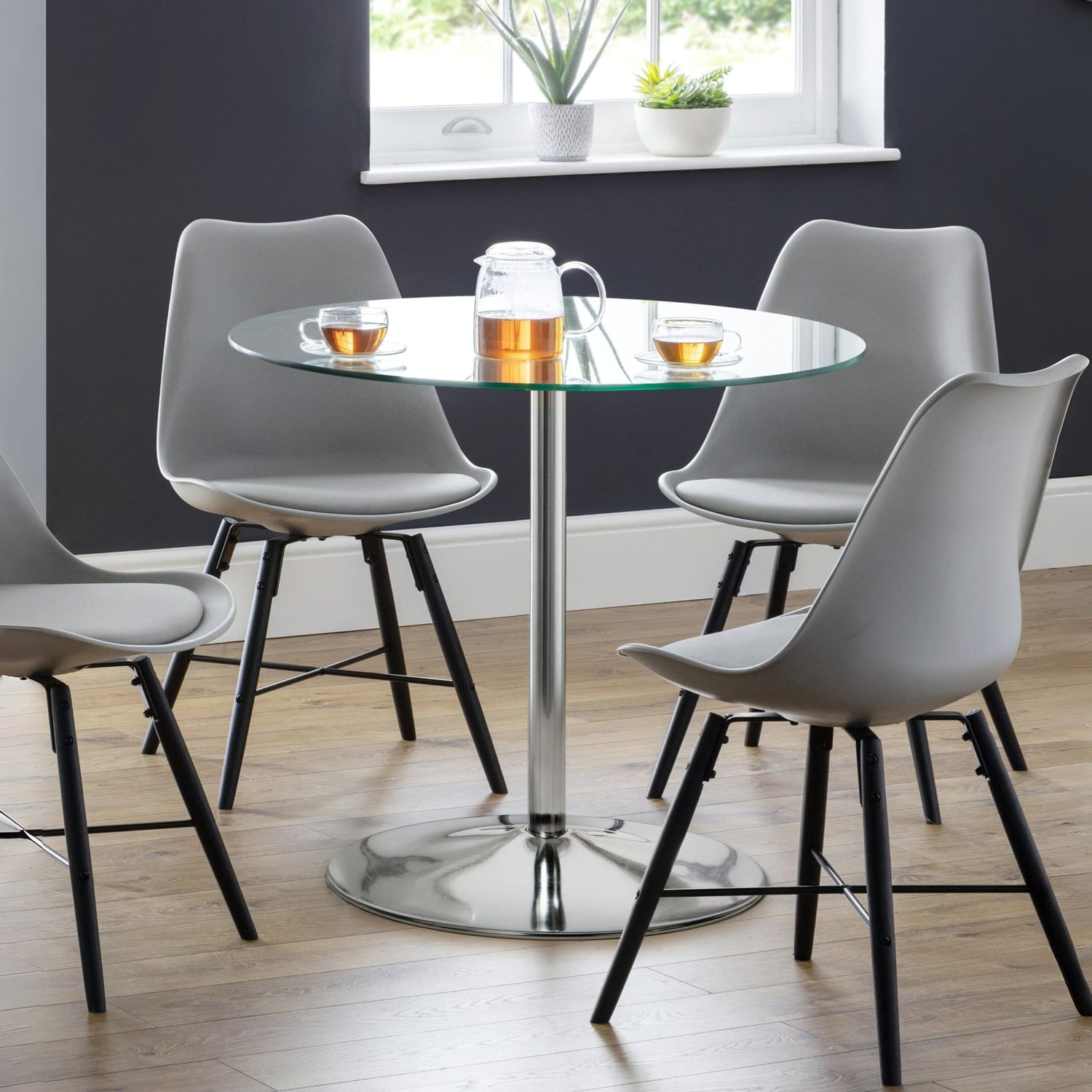 Dining room with a round glass table and four gray chairs.